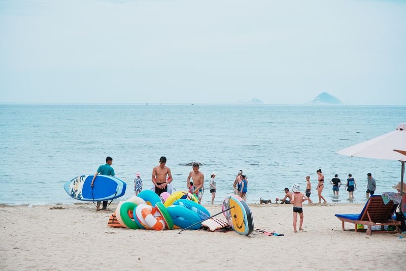 Families with paddleboards and floats at the water's edge
