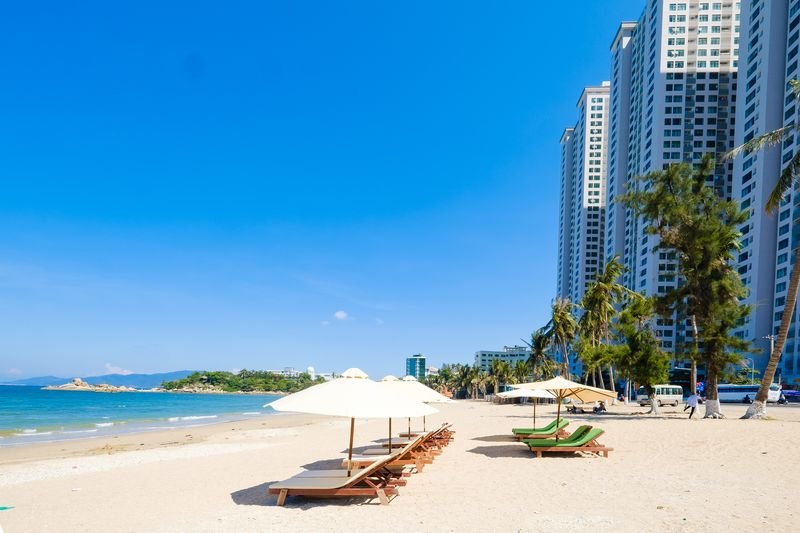 Wooden loungers under parasols facing the calm bay of Nha Trang