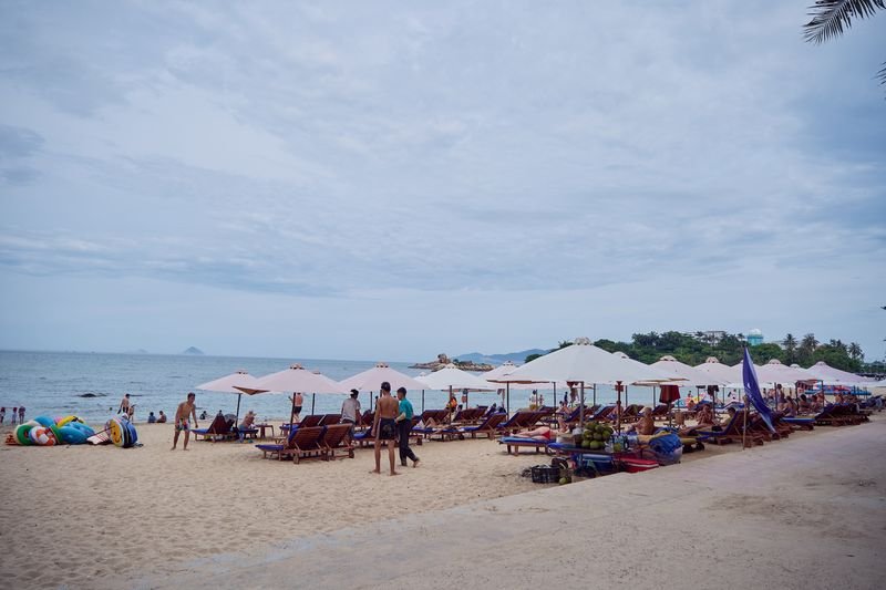 Guests relaxing under parasols on the beach on a soft morning