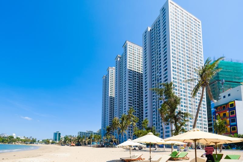 Beachfront residential towers rising behind palm trees on Hon Chong beach