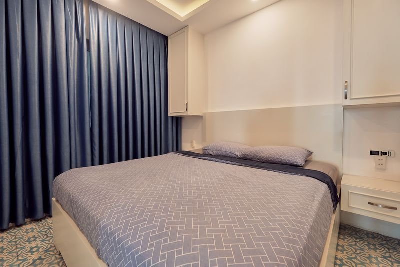 King bed with soft grey linen and warm cove lighting