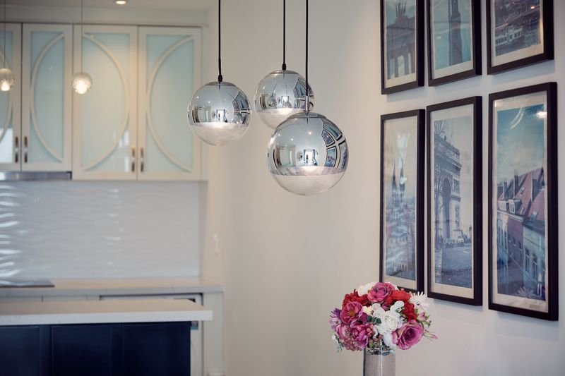Chrome globe pendant lamps beside framed travel prints