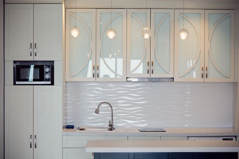 Kitchen detail with chrome pendant lamps and wave-pattern splashback