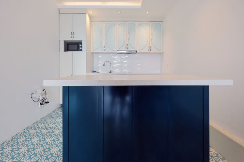 Navy kitchen island under warm spotlights