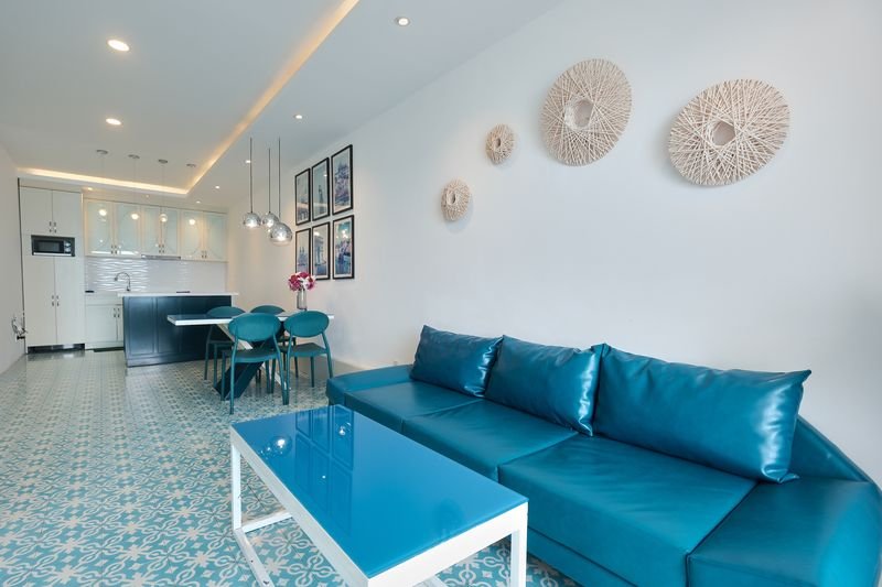 Villa living room with long teal sofa and rattan wall decor