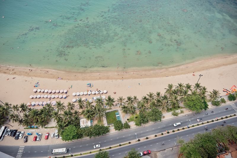 Bird's-eye view of the beach, palms and coastal road from the apartment