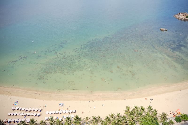Shallow turquoise lagoon and beach curve seen from a high floor